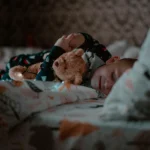 Petit enfant tenant tendrement son doudou en peluche dans son lit