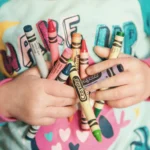 Petite fille dessinant avec des feutres colorés sur la table