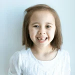 enfant qui montre fièrement sa première dent de lait tombée