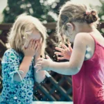 deux jeunes enfants en désaccord et parent qui apaise